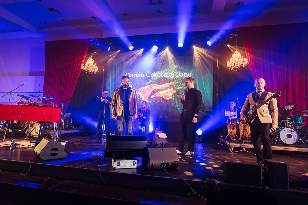 Marián Čekovský Band na pódiu pod obrazovkou s názvom kapely