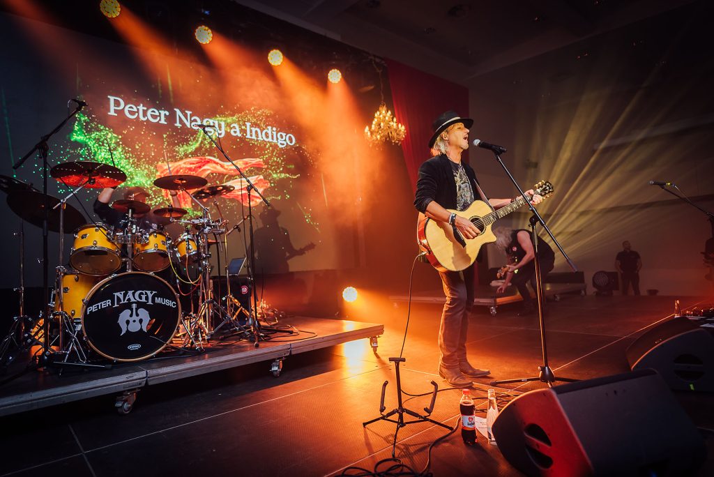 Peter Nagy a Indigo na pódiu s akustickou gitarou pri oranžovom svetle