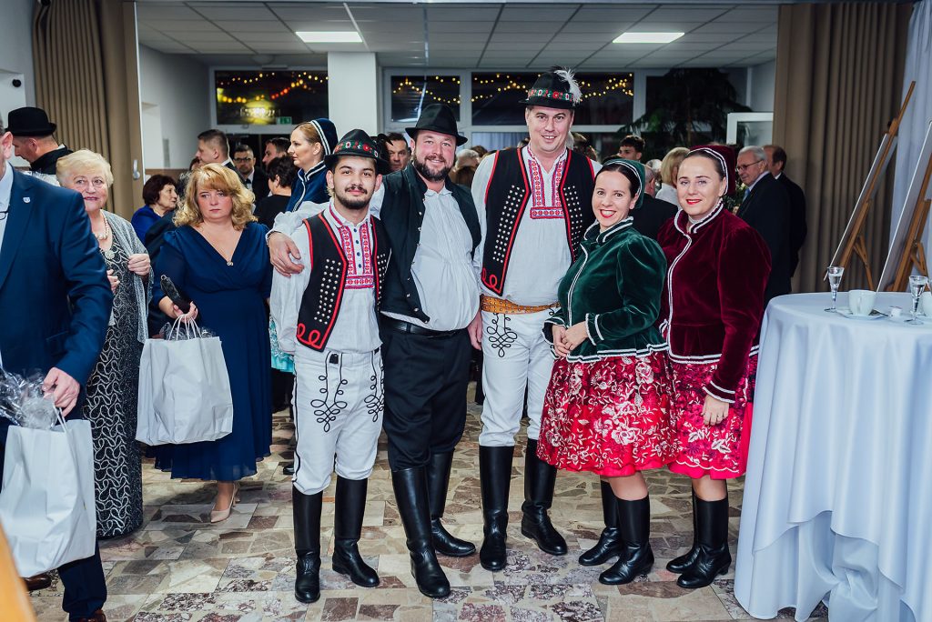 Hostia a folklórna skupina v krojoch vo foyer kultúrneho domu v Budmericiach