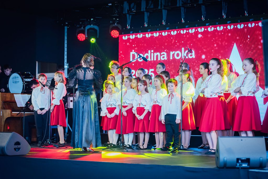 Žiaci ZUŠ Budmerice na pódiu v bielo-červených krojoch so zbormajsterkou
